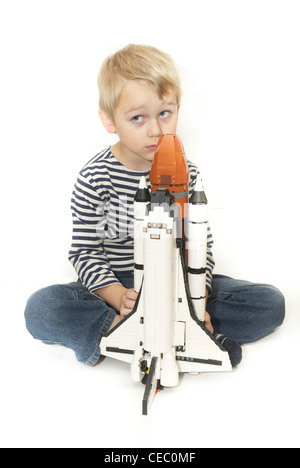 Kind blonden Jungen spielen mit Lego Space Shuttle Modell Spielzeug Ausschneiden Stockfoto