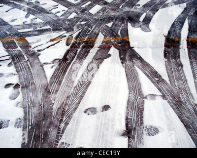 Fußspuren und Reifenspuren im Schnee. Stockfoto