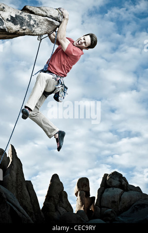 Kletterer kämpft um seinen nächsten Griff auf einer anspruchsvollen Klippe zu erreichen. Stockfoto