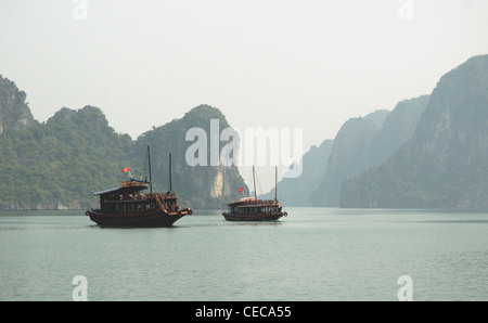 Pause in Vietnams Ha Long Bucht zwei umgebaute Dschunken im hellen türkisfarbenen Wasser unter den charakteristischen Kalktürmen der Bucht Stockfoto