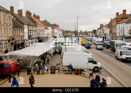 Besetzt belebten malerische Stadt (Northallerton High Street) am Markttag (Stände, Leute einkaufen, Fahrzeuge auf der Straße, Geschäfte) - North Yorkshire, England, UK. Stockfoto