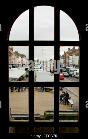 Blick durch das Fenster der hektischen geschäftigen Stadt (Northallerton High Street) am Markttag (Stände, Leute, Straße) - North Yorkshire, England, UK. Stockfoto