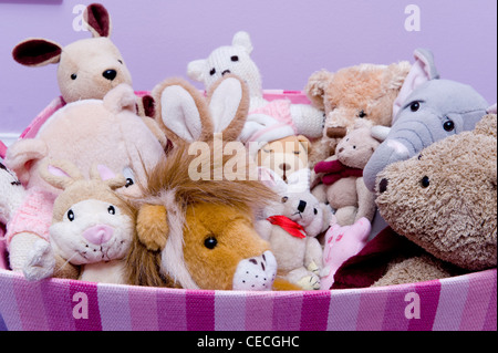 Close-up (Mädchen-) Rosa gestreifte Spielzeugkiste des Kindes voll nach oben mit verschiedenen Soft Toys (Teddies, Elefanten, Löwen, Kaninchen) - Yorkshire, England, UK. Stockfoto