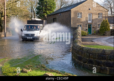 Überschwemmung - Lkw (Männer in der Kabine) Fahren & Spritzwasser durch tiefe Hochwasser auf überfluteten Landstraße nach schweren Regenfällen - North Yorkshire, England, UK. Stockfoto