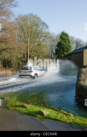 Überschwemmung - silver Auto (BMW) Fahren & Spritzwasser durch tiefe Hochwasser auf überfluteten Landstraße nach schweren Regenfällen - North Yorkshire, England, UK. Stockfoto