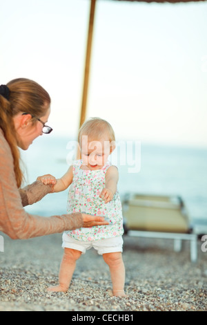 Baby spielt mit Mutter am Strand Stockfoto