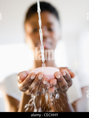 Wasser spritzt auf Seife in schwarz Frauenhand Stockfoto