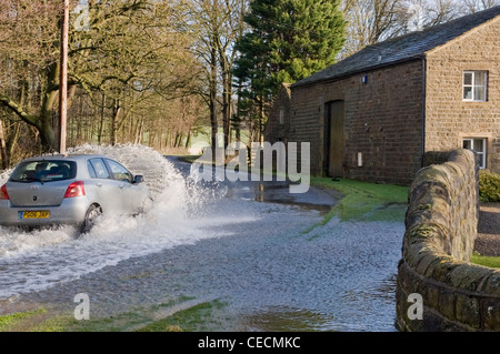 Überschwemmung - silver Auto (Toyota) Fahren & Spritzwasser durch tiefe Hochwasser auf überfluteten Landstraße nach schweren Regenfällen - North Yorkshire, England, Großbritannien Stockfoto