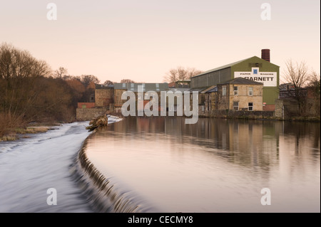 River Wharfe Wasser sanft fließende & Kaskadierung über Wehr unter Sonnenuntergang Himmel, historische Granat der Papierfabrik jenseits - Otley, West Yorkshire, England, UK. Stockfoto