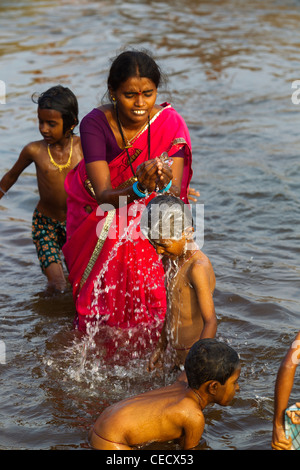 Aktivitäten am Tungabhadra Fluss in Hampi. Mutter Baden seinen Sohn an den Wassern von Tungabhadra Fluß, Hampi, Karnataka, Indien Stockfoto