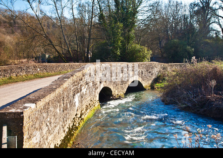 Eine gewölbte Cotswoldstone Brücke über einen kleinen Fluss von Bach in dem Dorf Slaughterford, Wiltshire, England, UK Stockfoto