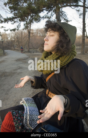 Junge Frau versucht, etwas Wärme von der Sonne an einem Winternachmittag zu absorbieren. Stockfoto