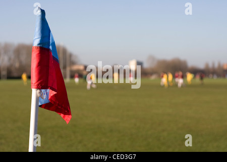 Fußball-Fußballspiel mit blauen und roten Eckpfosten mit Fahne, zwei Mannschaften spielen im Hintergrund am Hackney Sümpfe, London Stockfoto