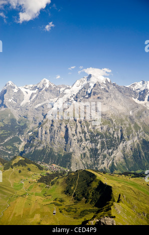 Vertikale Ansicht der Schilthorn Luftseilbahn mit spektakulärem Blick auf die Jungfrau, Mönch und Eiger an einem sonnigen Tag. Stockfoto