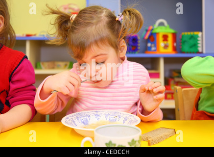 Kleines Mädchen isst im kindergarten Stockfoto