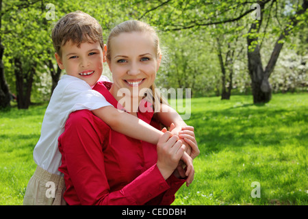 Sohn umarmt hinter Mutter im Park im Frühjahr Stockfoto