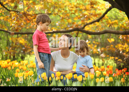 Mutter mit Kindern im Garten im Frühling unter blühenden Tulpen Stockfoto