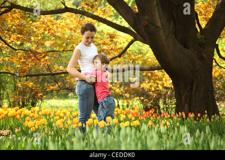 Sohn nimmt Mutter im Garten im Frühling unter blühenden Tulpen Stockfoto