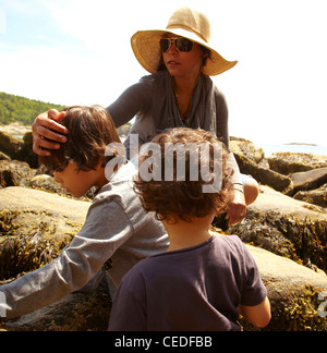 Mutter und Söhne sitzen auf Felsen Stockfoto