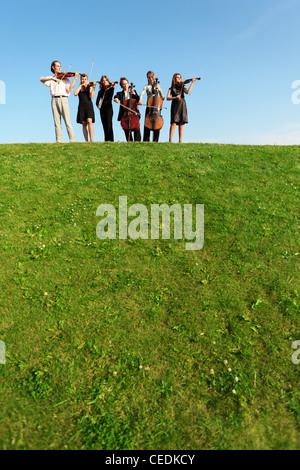 Gruppe von Musikern spielen Geigen auf Hügel gegen Himmel Stockfoto