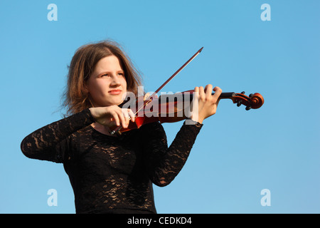 Mädchen spielt Geige gegen Himmel Stockfoto