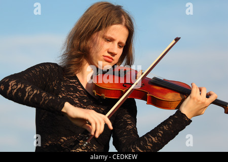 Mädchen spielt Geige gegen Himmel Stockfoto