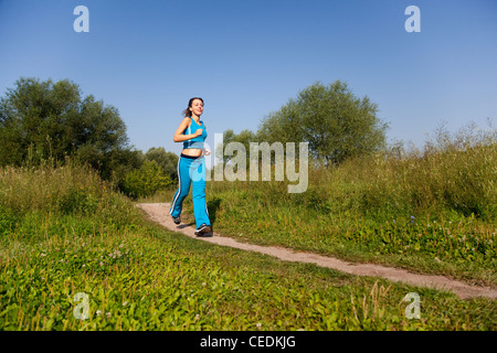 junge attraktive Frau läuft im Land Stockfoto