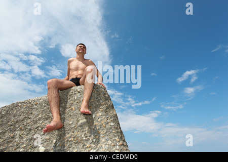 Mann in rutscht sitzt auf Fels, Ansicht von unten, horizontalen Schuss Stockfoto