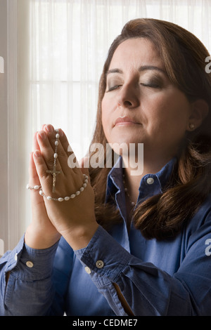 Hispanic Frau Rosenkranz beten Stockfoto