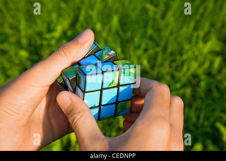 Würfel in der Weise des Planeten Land in der Hand auf Grund des Krauts Stockfoto