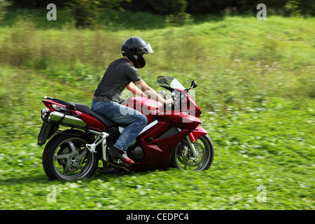 Motorradfahrer auf der Wiese Reiten Stockfoto