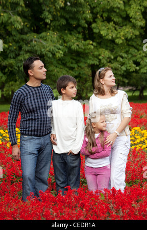 vierköpfige Familie sucht beiseite im blühenden park Stockfoto