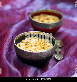 Zwei indischen Basmati-Reis-Pudding in Schalen mit einem silbernen Löffel auf einem bestickten lila Tuch, Nahaufnahme Stockfoto