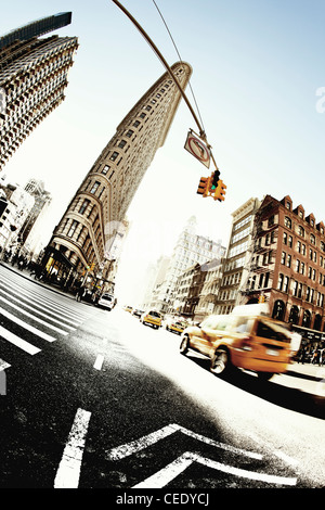 Flatiron building, New York mit Taxi cabs vorbeifahren, aufgenommen mit einer ultra-breite 15mm fisheye-Objektiv aus einem niedrigen Winkel Stockfoto