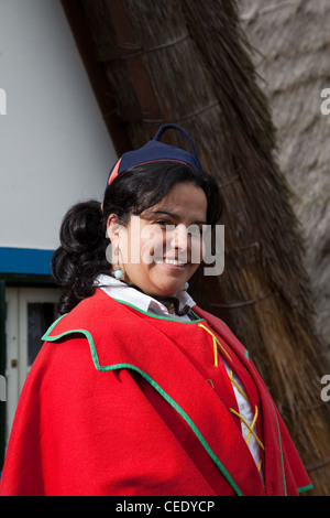 Traditionelles, dreieckiges portugiesisches Haus mit einem Strohdach von Palheiro. Frau in traditioneller Tracht aus mehrfarbigen Stoffen Santana, Madeira Stockfoto
