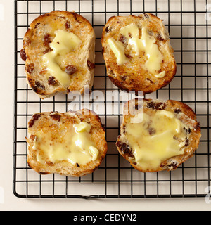 vier mit Butter gerösteten Hot Cross Buns auf Kuchengitter Stockfoto