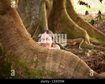 Mädchen auf der Suche hinter Wurzeln der Moreton Bay Feigenbaum Stockfoto