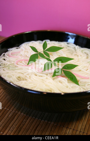 Gekocht, authentische japanische Küche, Essen, Gerichte zubereitet. Rosa farbigen Somen Nudeln in schwarz Schüssel auf Bambus Tischset. Stockfoto