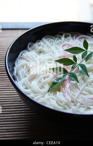 Gekocht, authentische japanische Küche, Essen, Gerichte zubereitet. Rosa farbigen Somen Nudeln in schwarz Schüssel auf Bambus Tischset Stockfoto