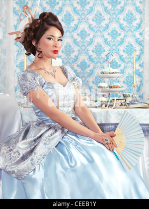 Führerschein und Fingerabdrücke bei MaximImages.com - wunderschöne asiatische Frau in einem schicken blauen Kleid auf einer Teeparty mit festlichem Tisch Stockfoto