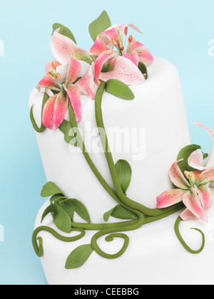 Torte, dekoriert mit Lilien auf blauem Hintergrund isoliert Stockfoto
