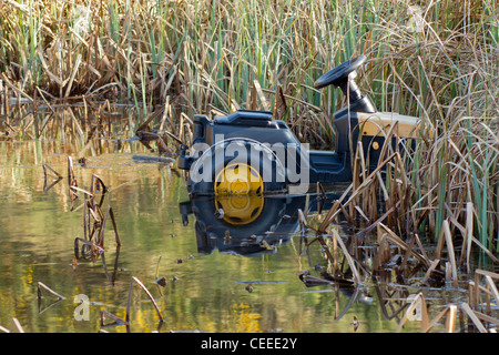 Ein Kind Spielzeug-Traktor in einem Schilf-Teich in Camborne. Cornwall UK. Stockfoto