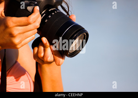 Ein Mädchen-Hände halten eine DSLR-Kamera, wie sie konzentriert ist, um ein Foto von etwas machen in der Nähe der Erde. Stockfoto