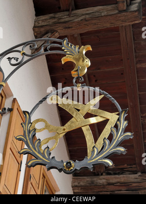 Eine traditionelle Handwerker Schild hängen außerhalb ein Bekleidungsgeschäft in Mittenwald, Bayern, Deutschland. Stockfoto