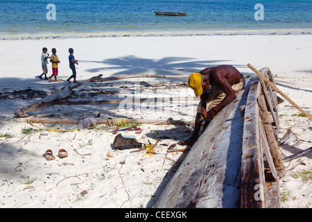 Zanzibari Greis Reparatur einer hölzernen Dhau am Strand von Bwejuu, Sansibar, Tansania Stockfoto