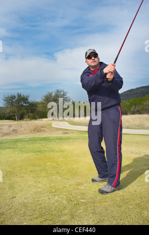 Männliche mittlere gealterte Golfspieler in Trainingsanzug nach Abschlag Stockfoto