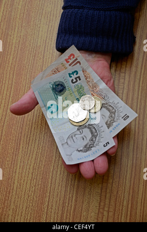 Männliche Rentner mit uk-Banknoten und-Münzen in der hand Stockfoto