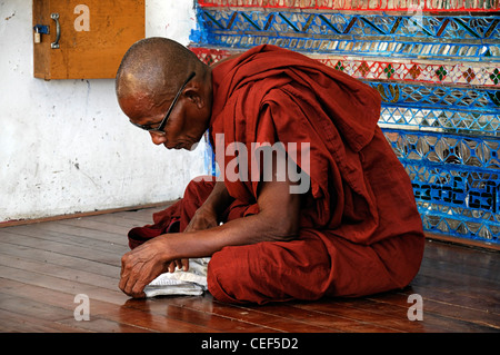 rote Roben buddhistischer Mönch lesen lesen beten beten Shwedagon Pagode Myanmar Burma Yangon Rangun Wahrzeichen historisches Denkmal Stockfoto