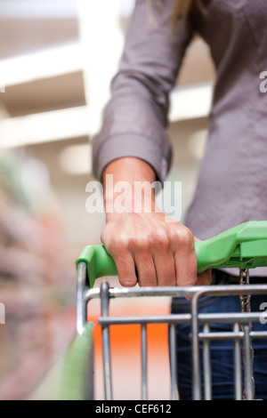 Junge Frau mit Schubkarre im Supermarkt auf der Suche nach Lebensmittel Stockfoto