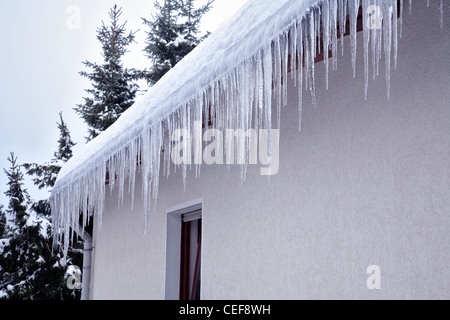 Eiszapfen hängen vom Schnee bedeckten Dach. Oberbergisches Land, Nordrhein Westfalen, Deutschland. Stockfoto